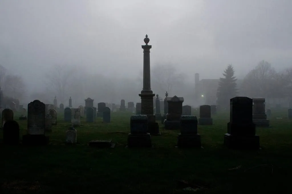 a tall tombstone and other tombstones in a graveyard